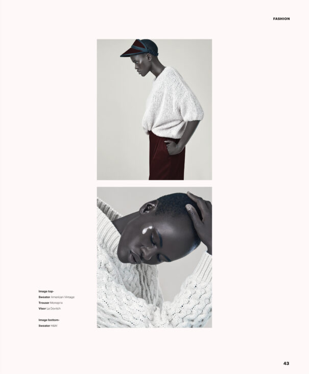 A woman wearing a white knit sweater and burgundy pants with hands on hips.