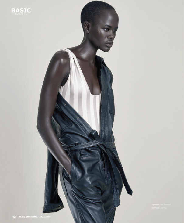 Black woman model with short hair wearing white striped top and black leather jacket.