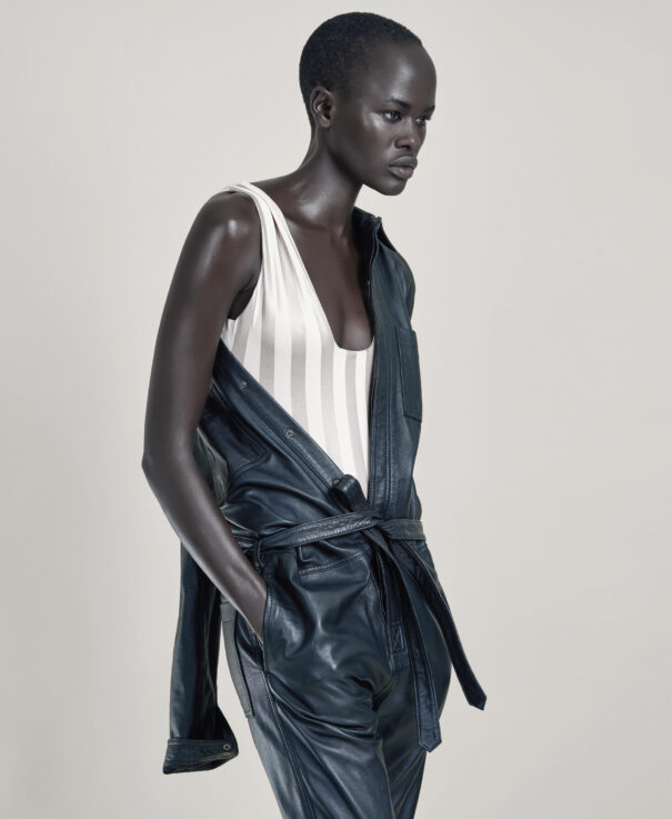 Black woman model with short hair wearing white striped top and black leather jacket.