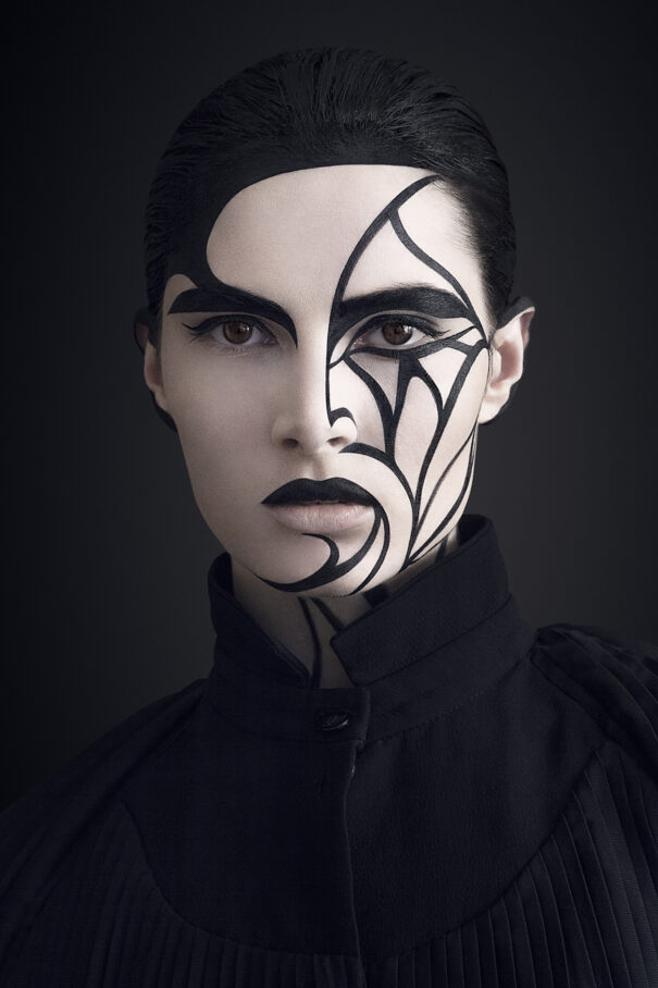 Black and white artistic face paint with bold lines on a person's face.