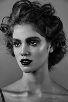 Black and white portrait of a woman with dramatic dark lipstick and curly hair.