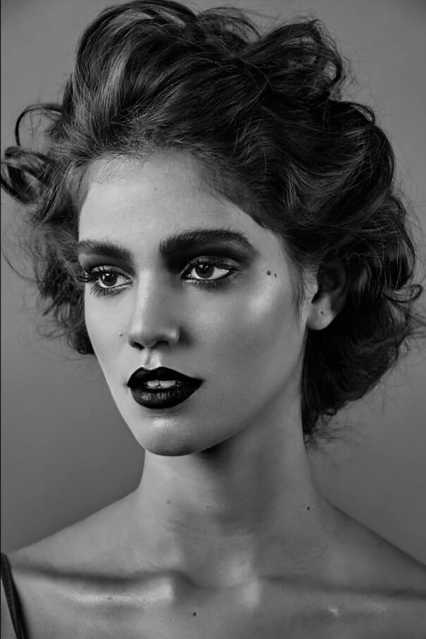 Black and white portrait of a woman with dramatic dark lipstick and curly hair.