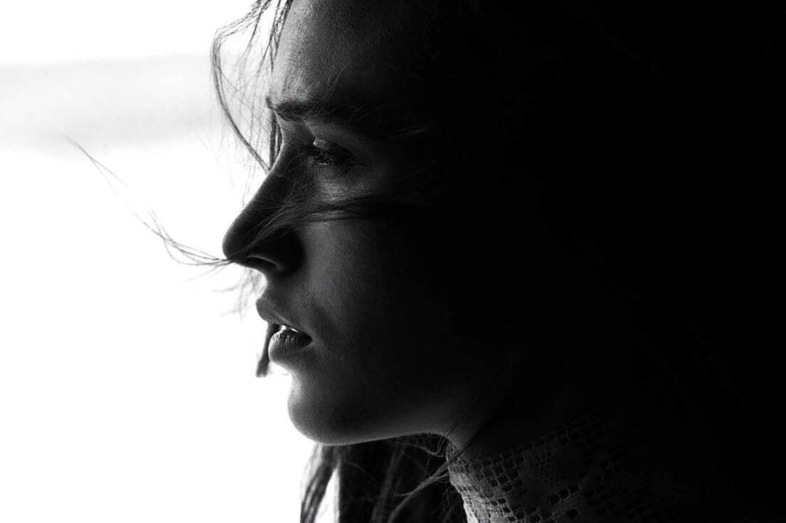 Silhouette of a woman with hair blowing in the wind, looking contemplative.