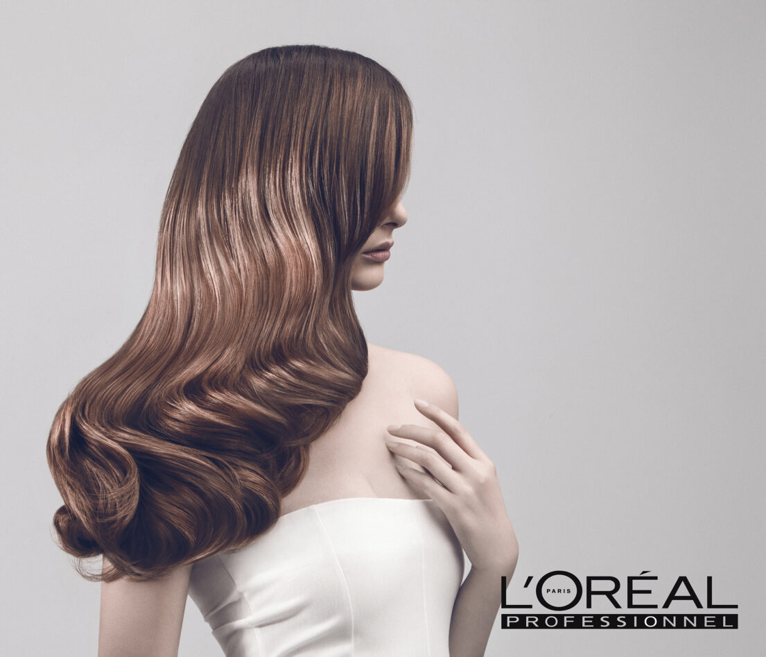 L'Oréal Professional advertisement featuring a model with long, wavy brown hair.