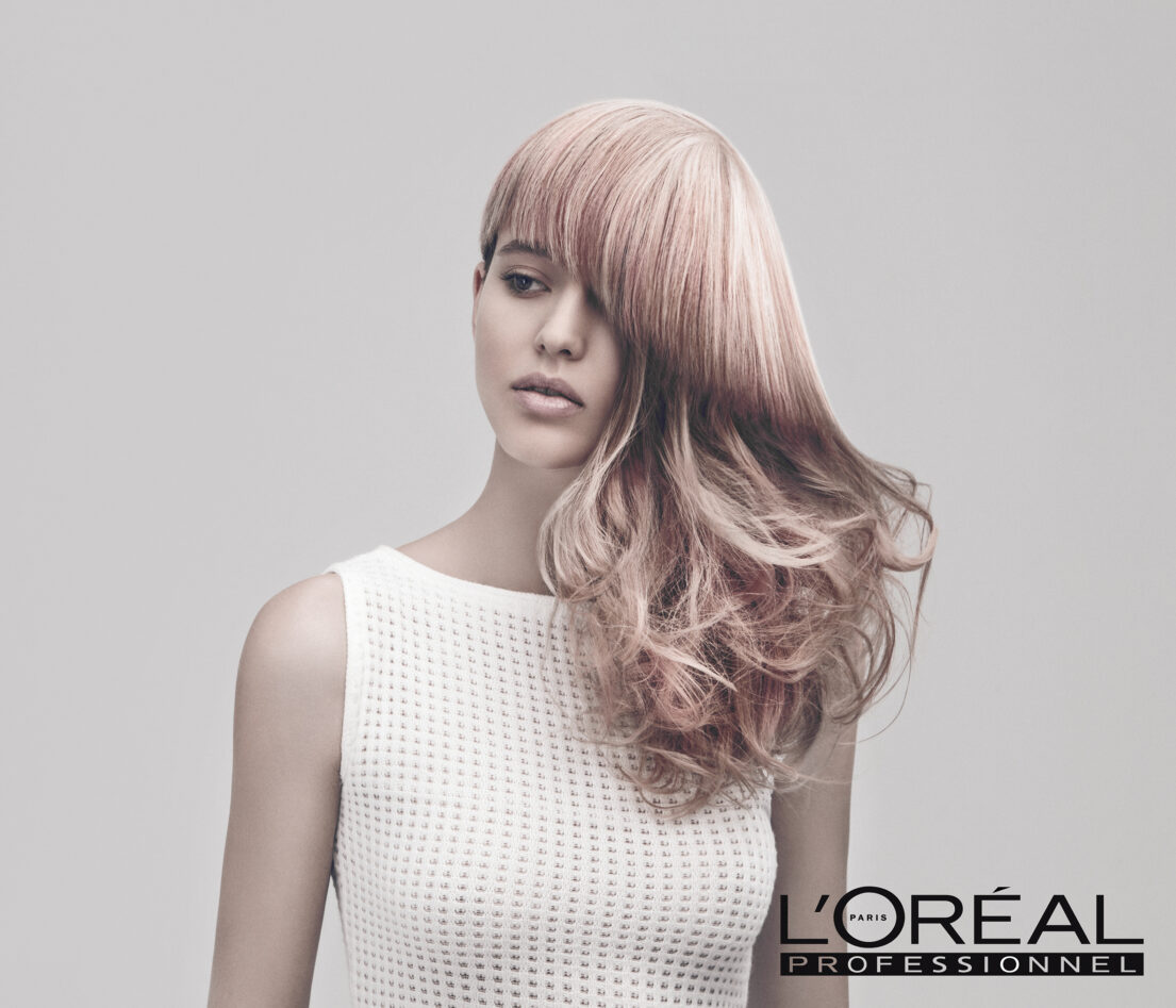 L'Oréal Professionnel advertisement featuring a woman with pink hair wearing a white top.